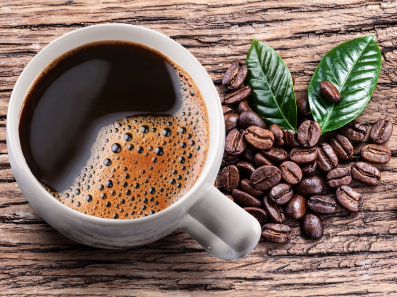 A Cup of Americano Coffee and Coffee Beans on a Wooden Table