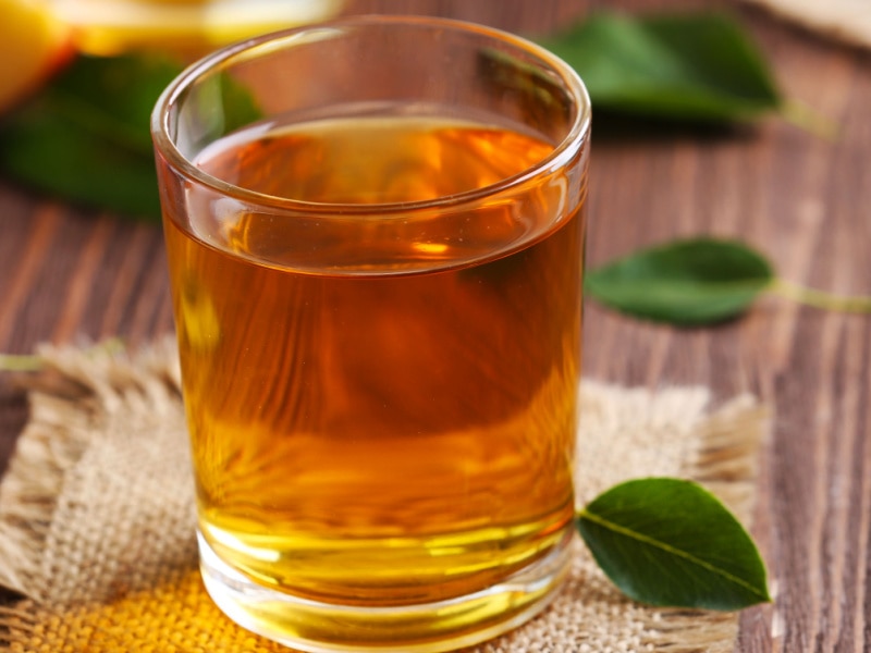 Glass of Apple Juice and Apple Leaves on a Wooden Table