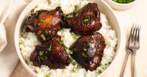 Bowl of Homemade Filipino Chicken Adobo with Chopped Onions and Rice