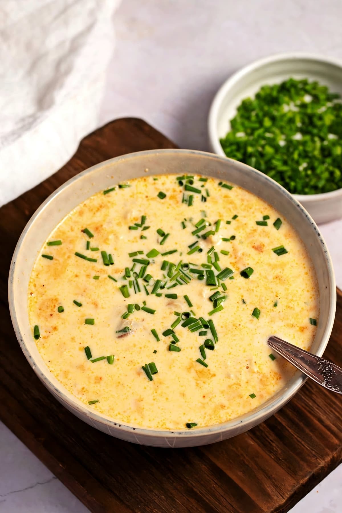 Bowl of Warm She Crab Soup Topped With Chives in a Wooden Board