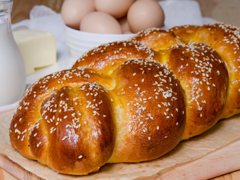 Loaf of Challah Bread with Sesame Seeds on a Wooden Cutting Board