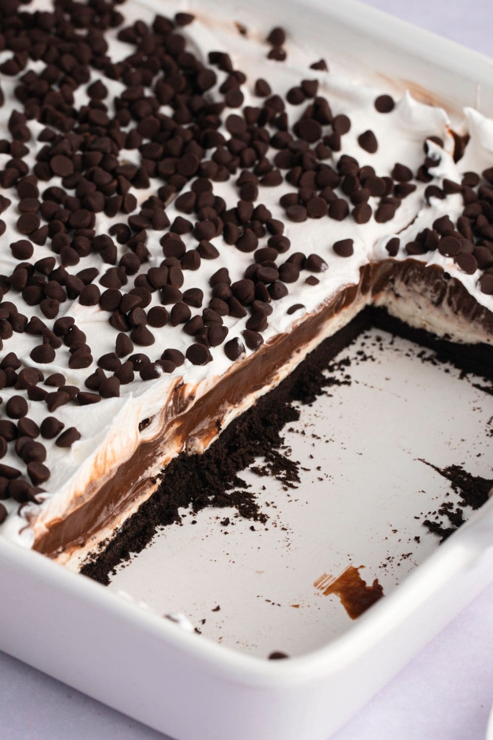 Homemade Oreo Lasagna with Chocolate Chips in a Baking Pan and a Few Slices Taken Out