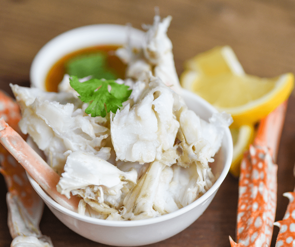 Crab Meat in a smal bowl with fresh herbs and lemon slices